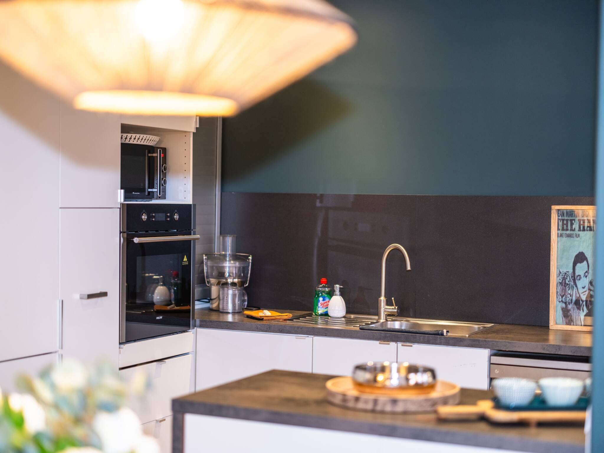 A modern kitchen with a built-in oven, a coffee machine, and a sink.