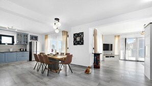 A modern kitchen with a dining area, a large window, and a dog sitting on the floor. - Enchanting Villa North with Pool and Jacuzzi (Krnica)