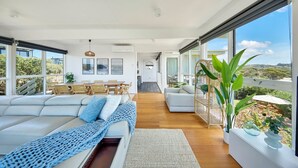 Een moderne woonkamer met een grote bank, een eethoek en uitzicht op de omgeving.