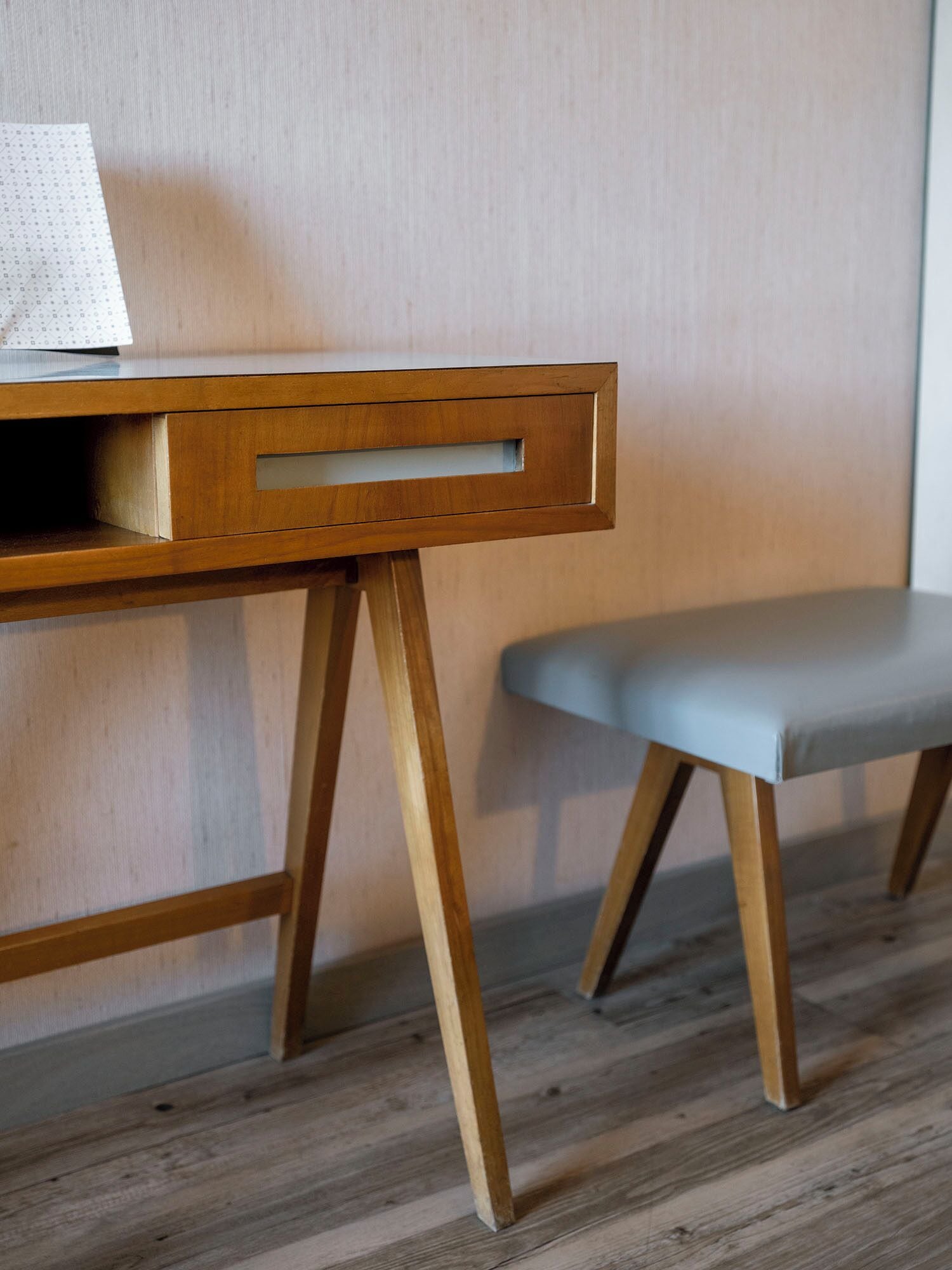 Un bureau en bois avec un tiroir et un banc doté d’un coussin.