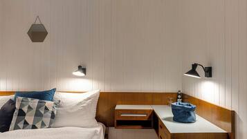 Une chambre à coucher avec un lit, une table de chevet et un petit tabouret.