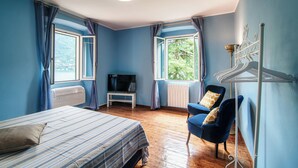 Un dormitorio con cama, una silla, televisión y radiador.