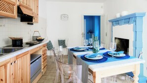Una cocina moderna con armarios de madera, una mesa de comedor preparada para cuatro comensales y una pared azul como detalle.