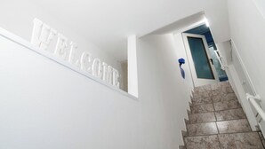Una escalera con un letrero que dice 'WELCOME', que lleva a una habitación con una flor azul y una puerta.