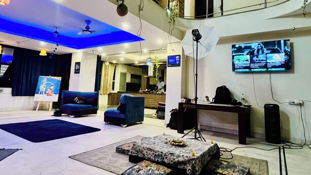 A spacious living area with a high ceiling, a balcony, and a flat-screen TV mounted on the wall. - Area 369 (Jaipur)