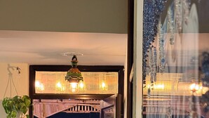 A cozy room with a bed, a hanging plant, and a view of the city at night. - Area 369 (Jaipur)