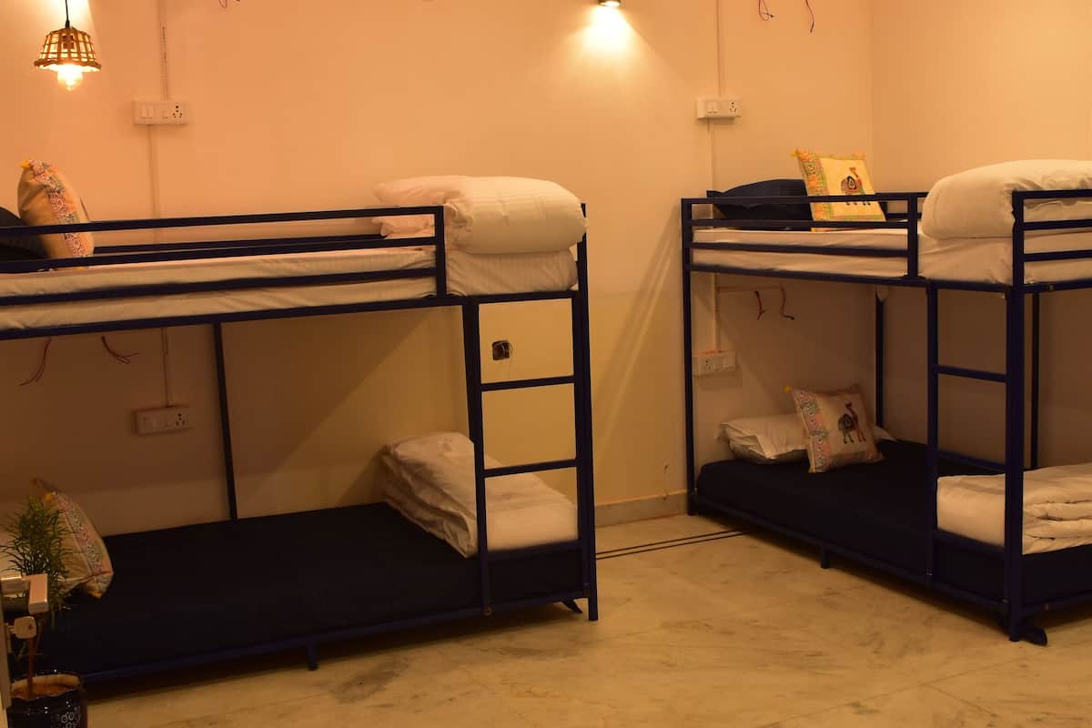 A room with bunk beds, a ceiling fan, and wall-mounted lights.