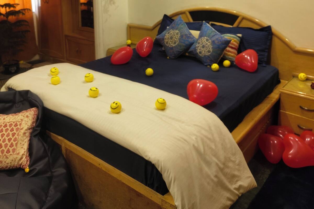 A bedroom with a bed, pillows, and hanging red balloons.