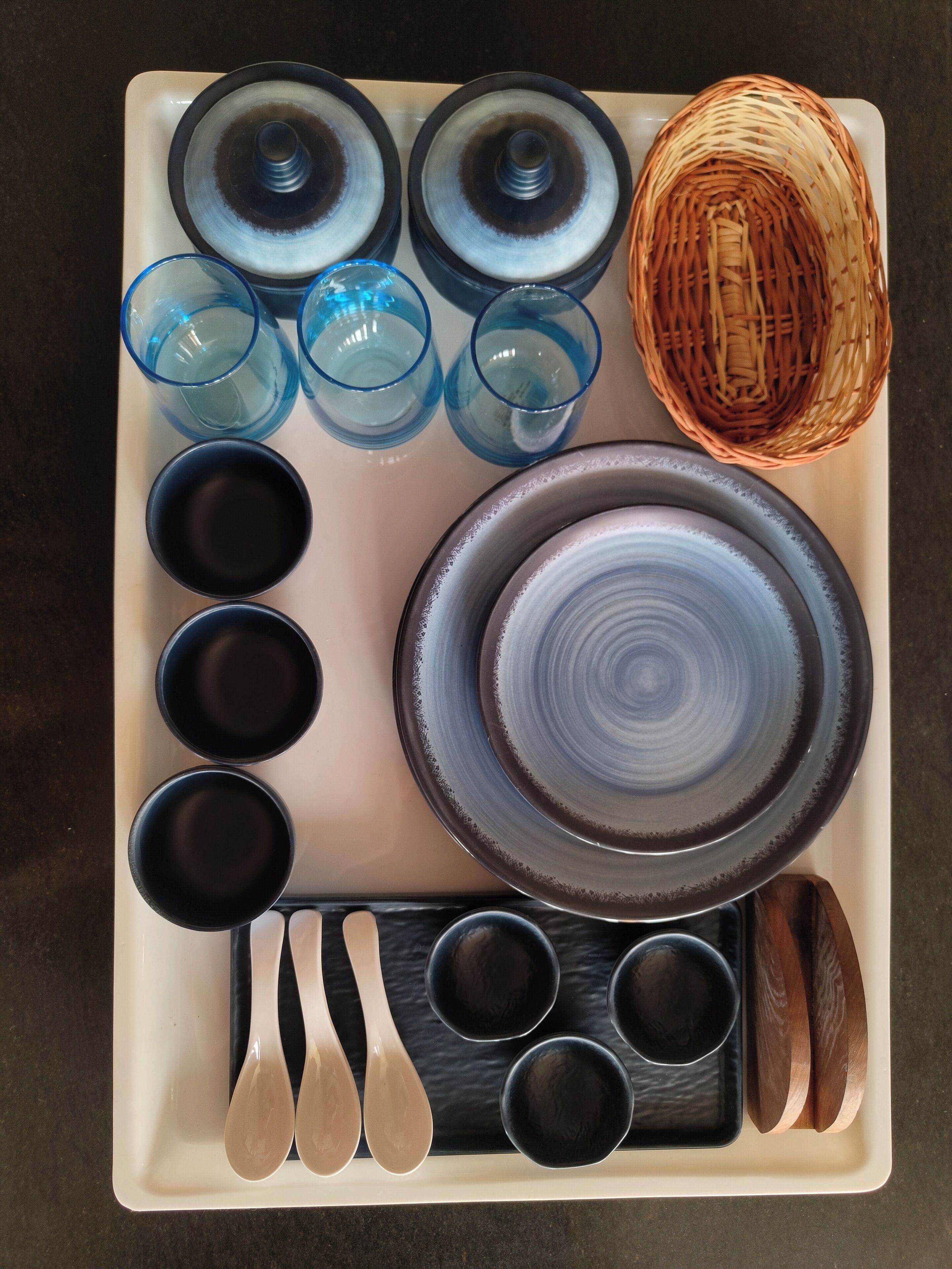 A tray with various kitchenware including bowls, cups, and spoons.