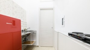 Et lille køkken med et rødt Hisense-køleskab, en hvid vask og en komfur.