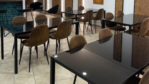 Une salle de conférence dotée de plusieurs tables et chaises, d’un grand écran et d’un mur décoratif en briques.