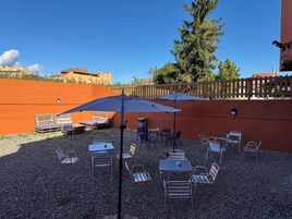 Un patio al aire libre con mesas, sillas, sombrillas y una cerca de madera.