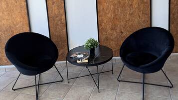 Two black chairs with metal frames, a small round table with a black surface, and a potted plant.
