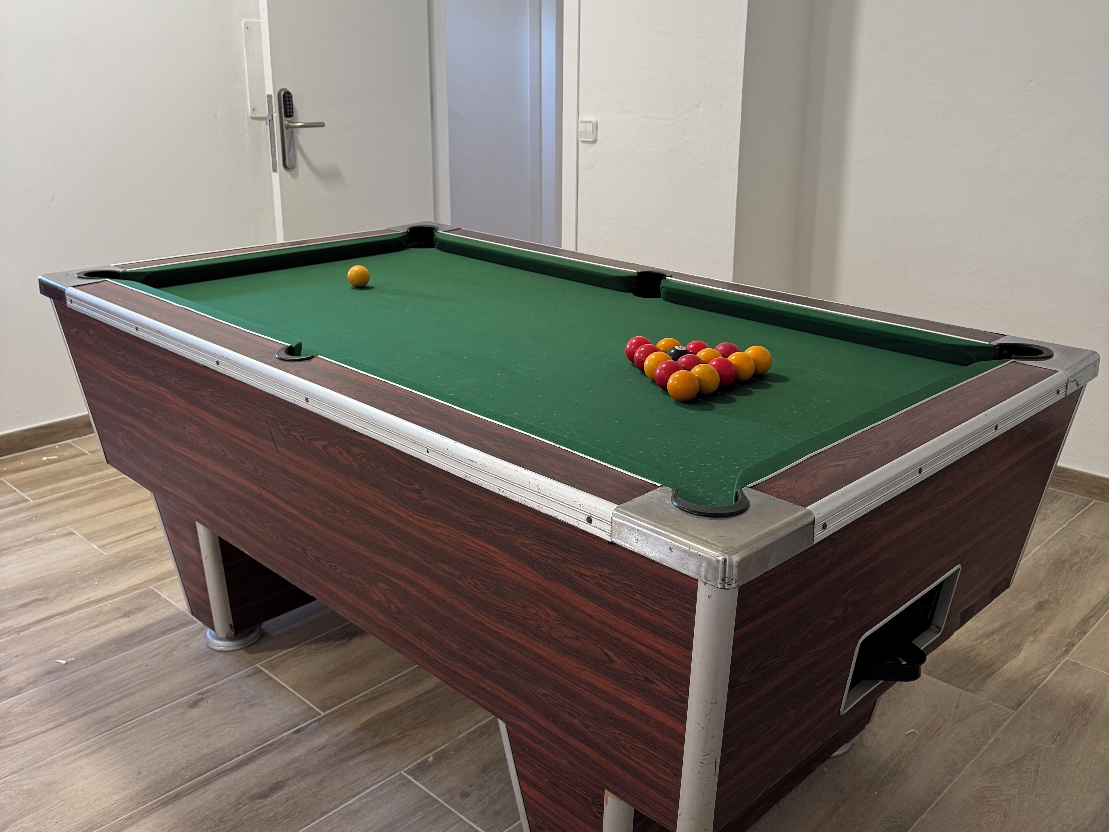 A pool table with a green felt surface, surrounded by a wooden frame.