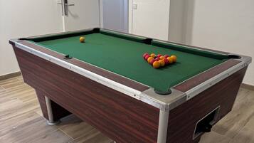 A pool table with a green felt surface, surrounded by a wooden frame.