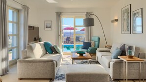 A modern living room with a sofa, armchair, and ottoman, a coffee table, and a view of a pool and outdoor seating. - Villa with pool in Istria for 8 persons, with a wonderful panoramic view  (Vižinada)