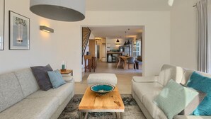 A modern living room with a sofa, ottoman, and a coffee table. There is a staircase leading to a kitchen area in the background. - Villa with pool in Istria for 8 persons, with a wonderful panoramic view  (Vižinada)