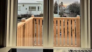 A window with a view of a building and a wooden deck.