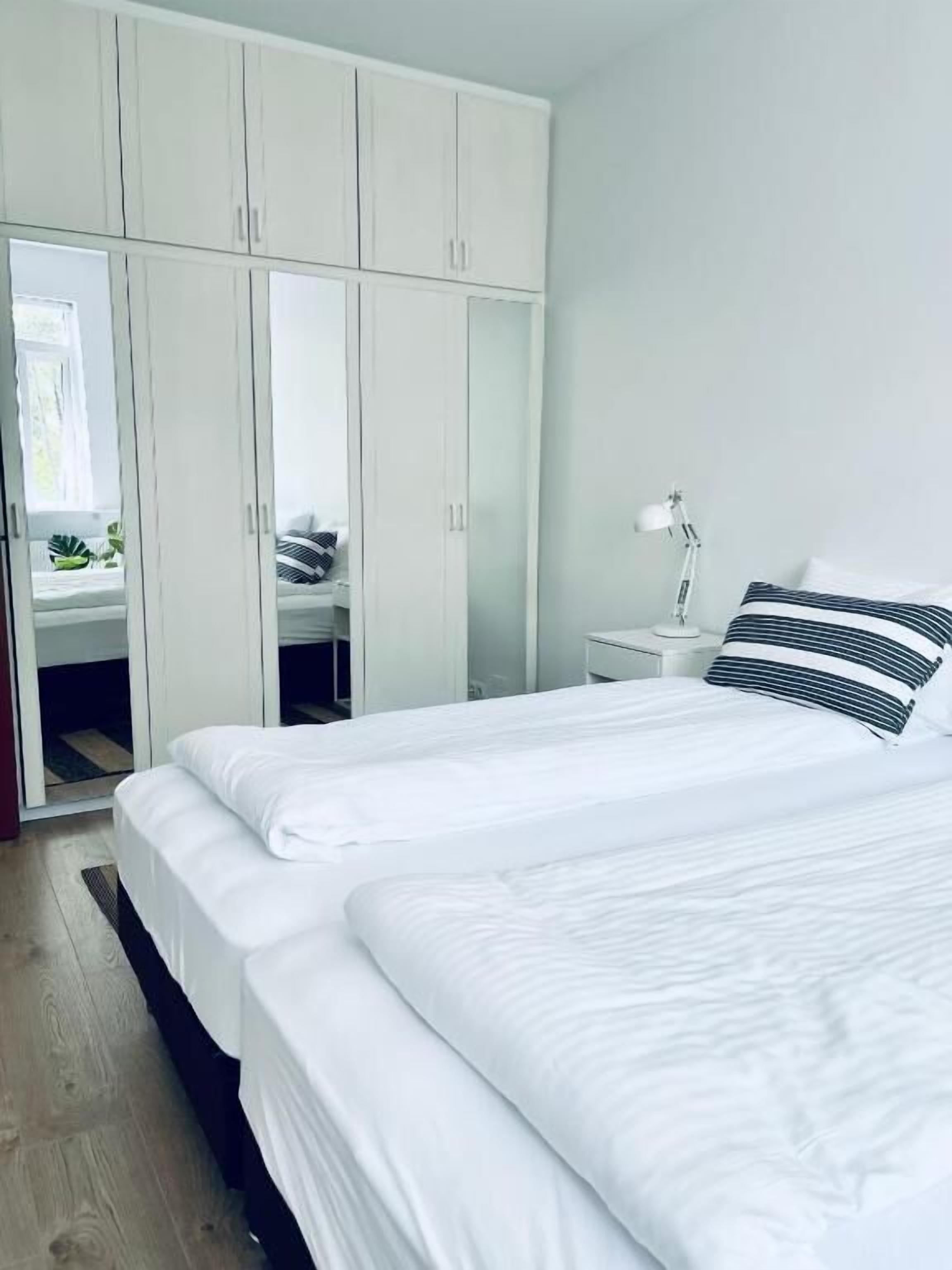 Une chambre à coucher avec un grand lit, une armoire blanche et une table de chevet avec une lampe.