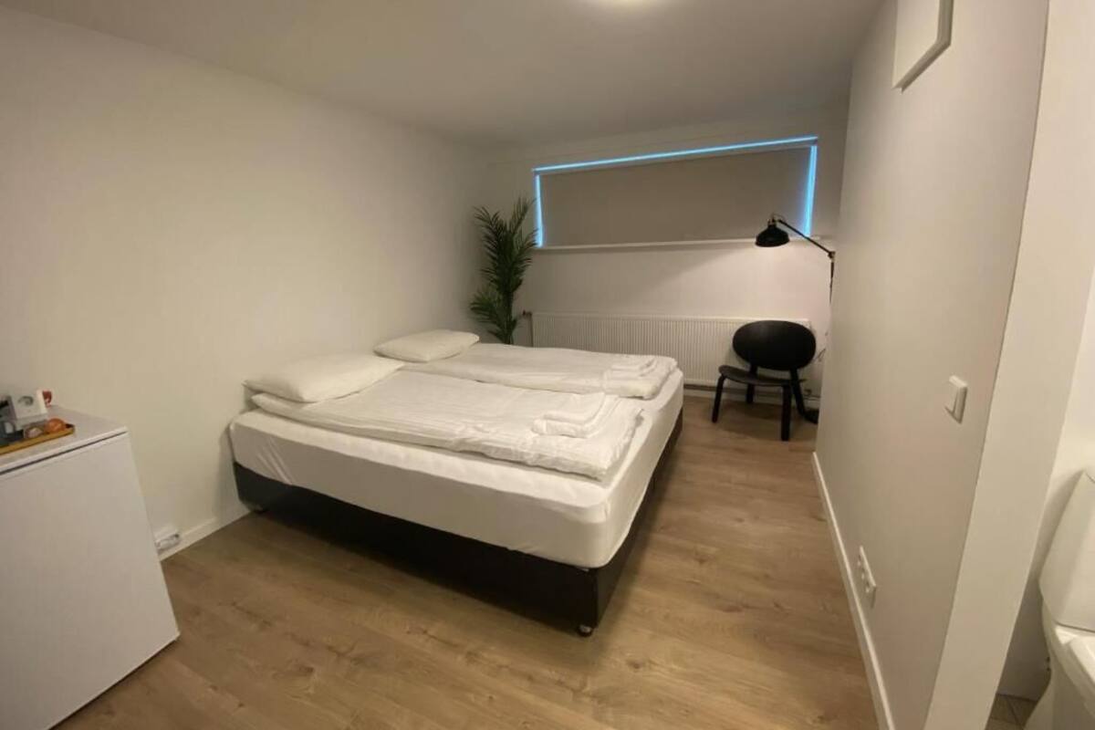 A bedroom with a bed, a desk, a chair, and a radiator.