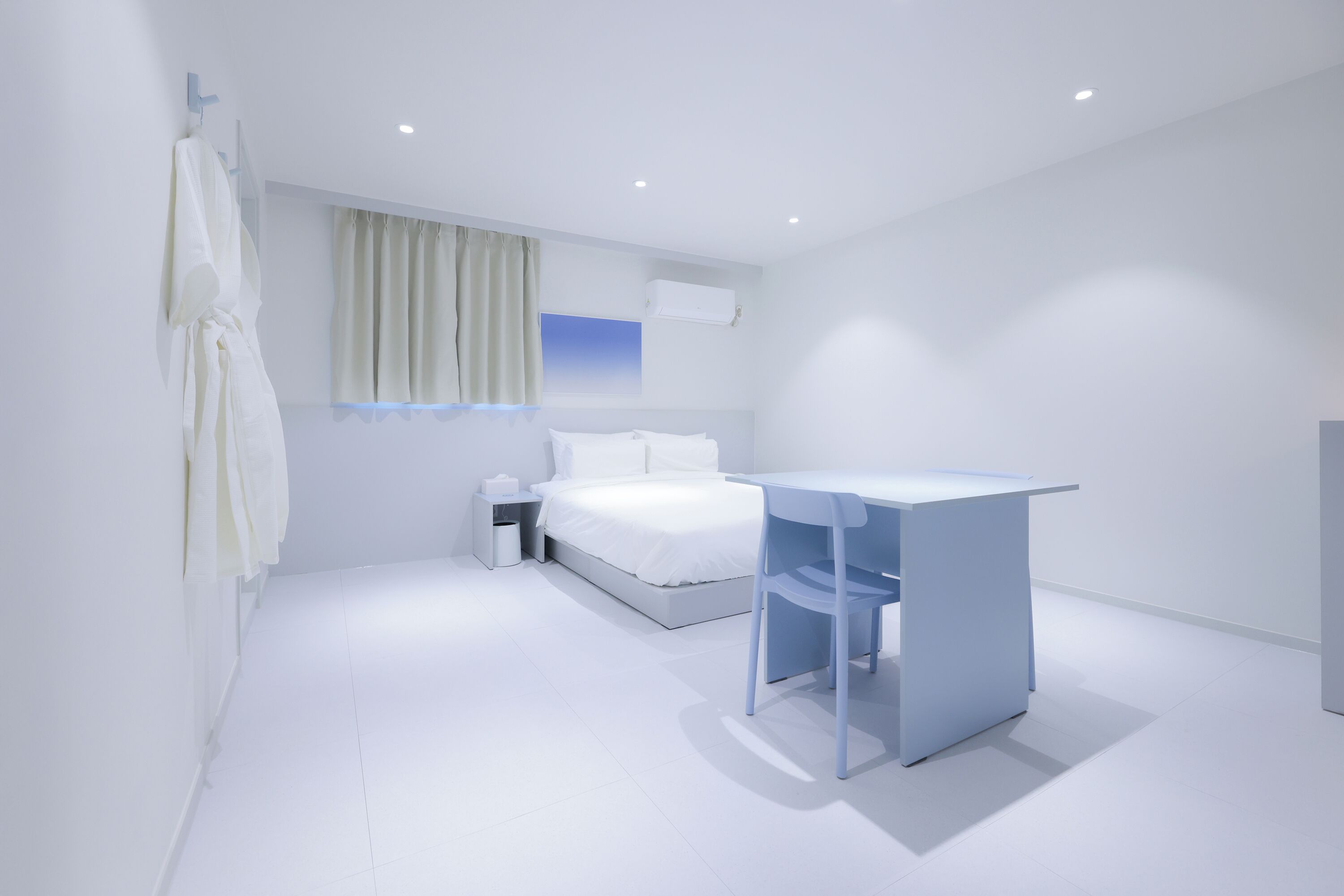 Ein modernes Hotelzimmer mit Bett, Schreibtisch und einem Vorhangfenster.