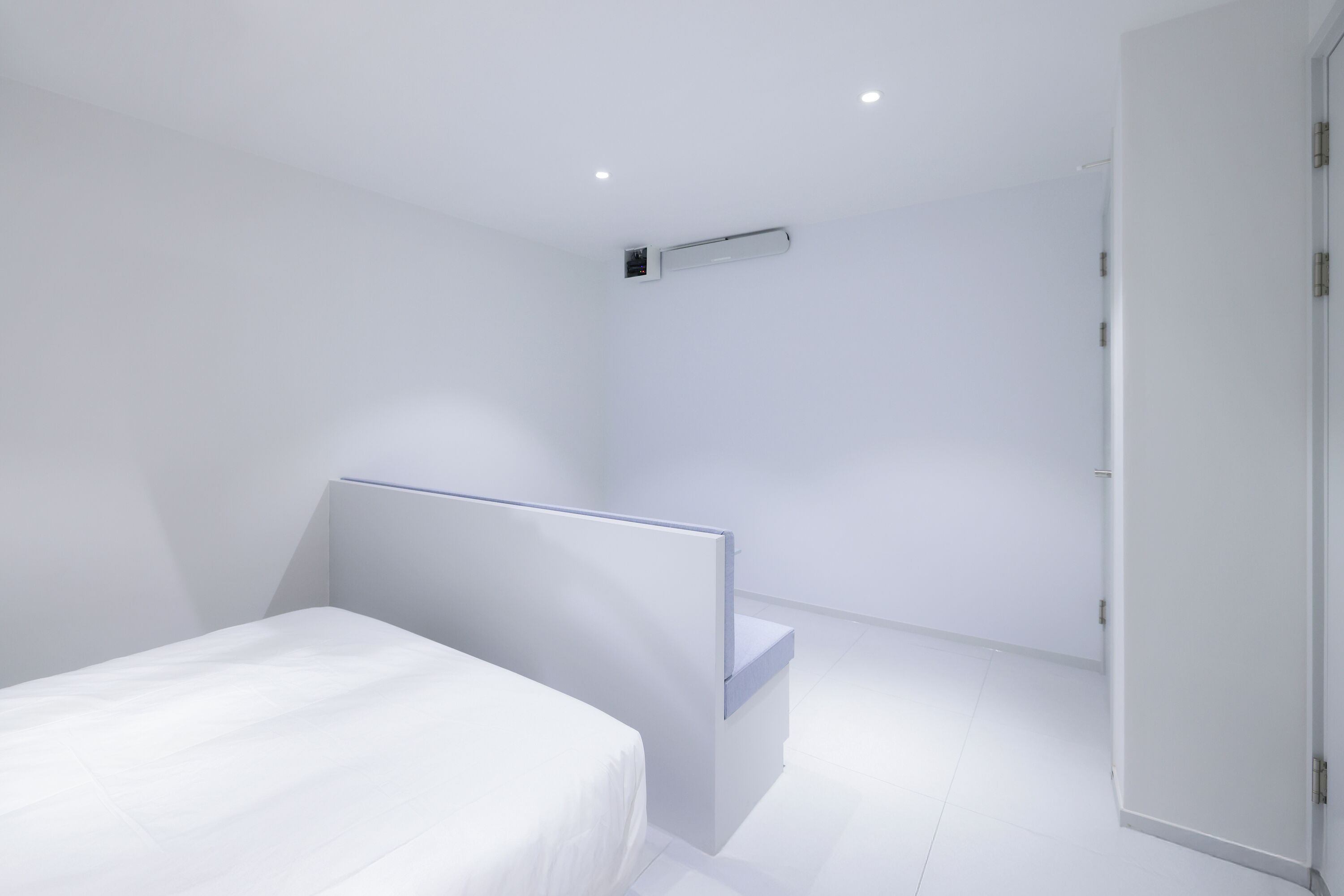A modern bedroom with a bed, a bedside table, and a built-in bench.