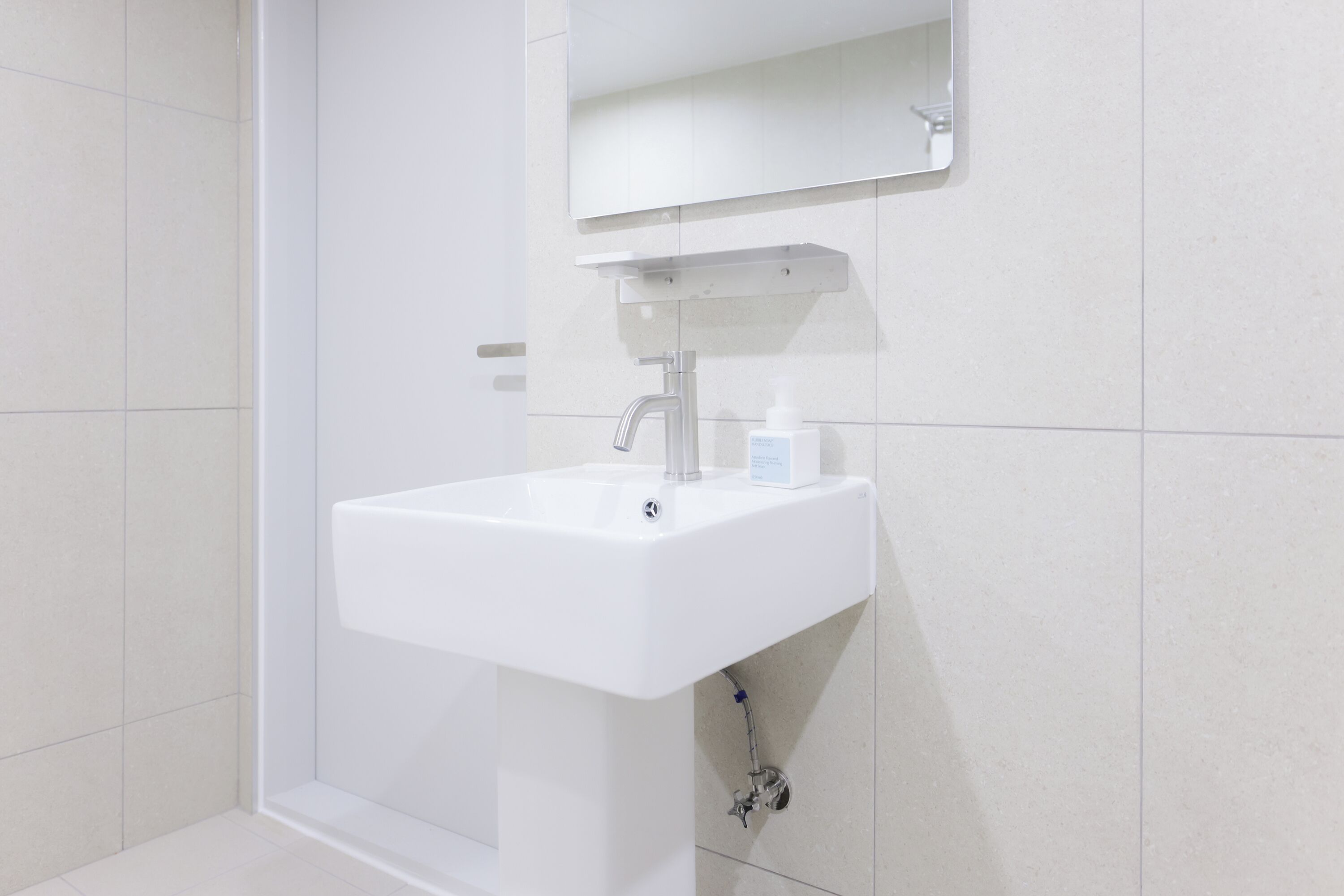 A white bathroom sink with a mirror above it, a soap dispenser, and a faucet.