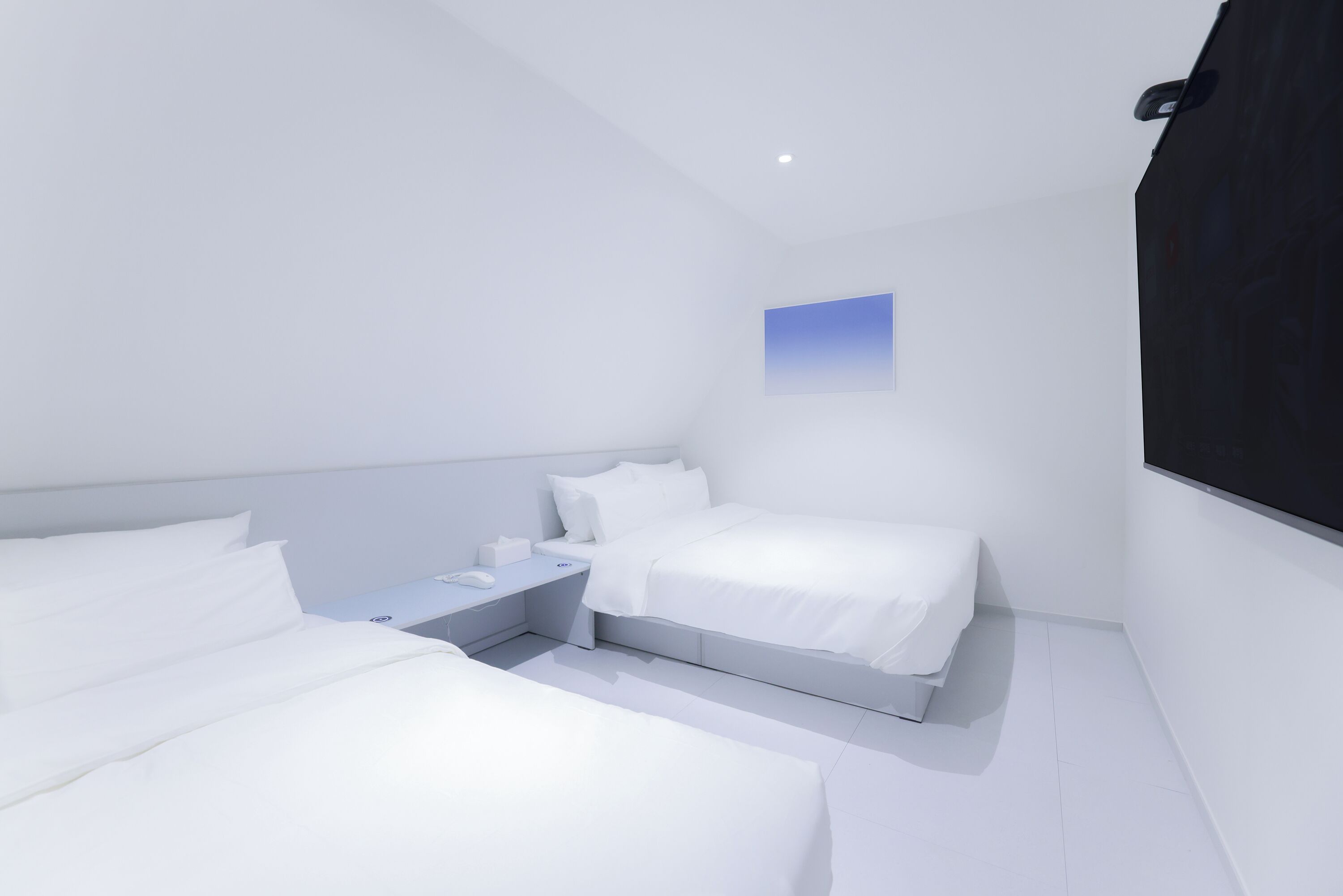 A modern, minimalist bedroom with a single bed, bedside table, and a small window.