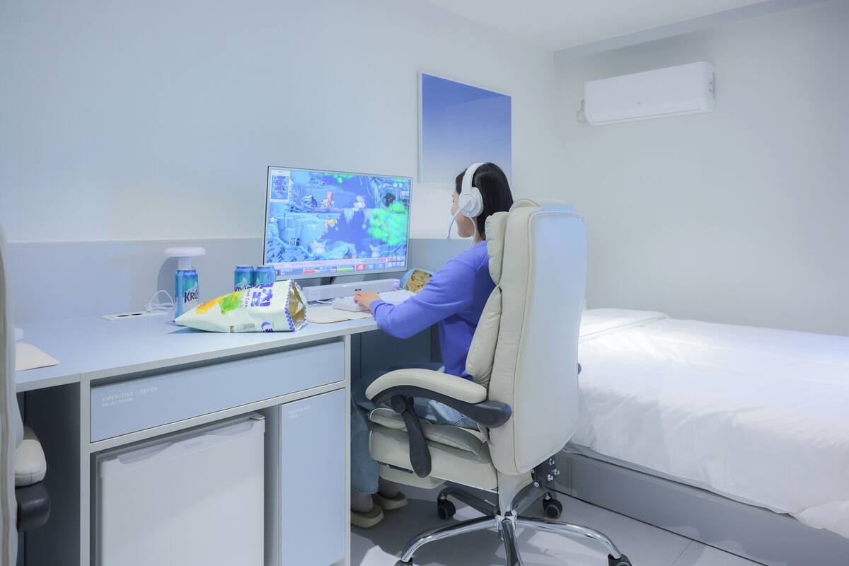 A hotel room with a bed, a desk with a computer, and a small refrigerator.