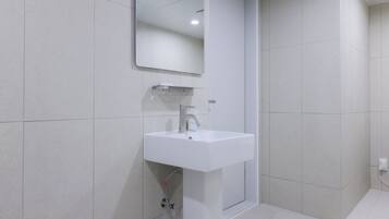 A modern bathroom with a white sink, mirror, and tiled walls.
