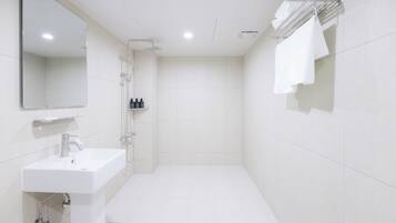 Un baño moderno con lavamanos, espejo y ducha blancos.