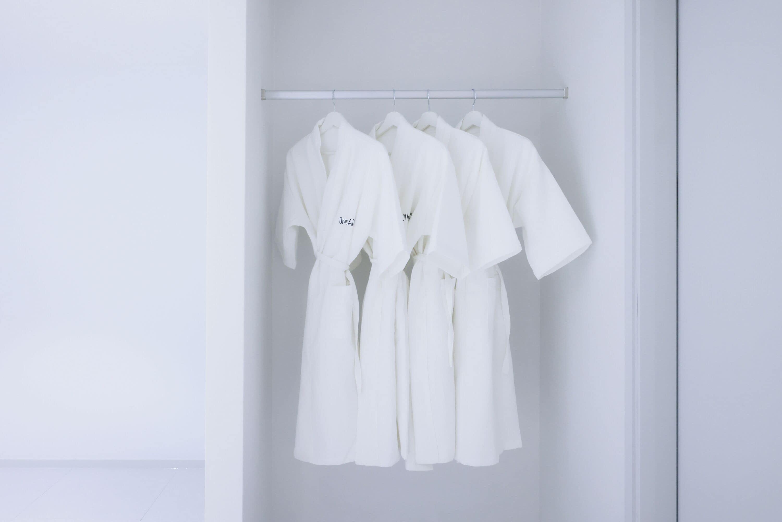 A white robe hanging on a rod in a minimalist room.