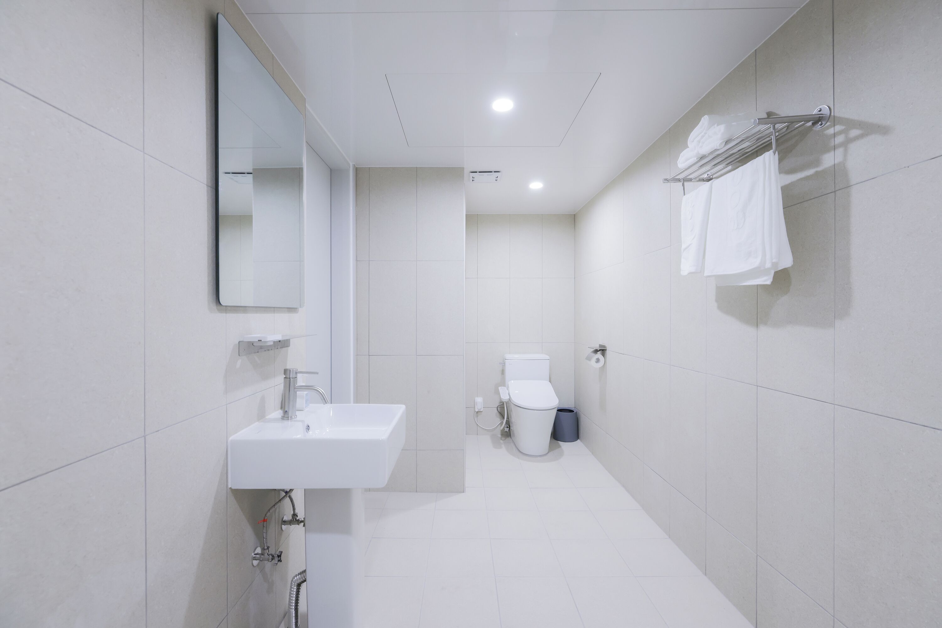 Un bagno moderno con lavandino, specchio e portasciugamani.