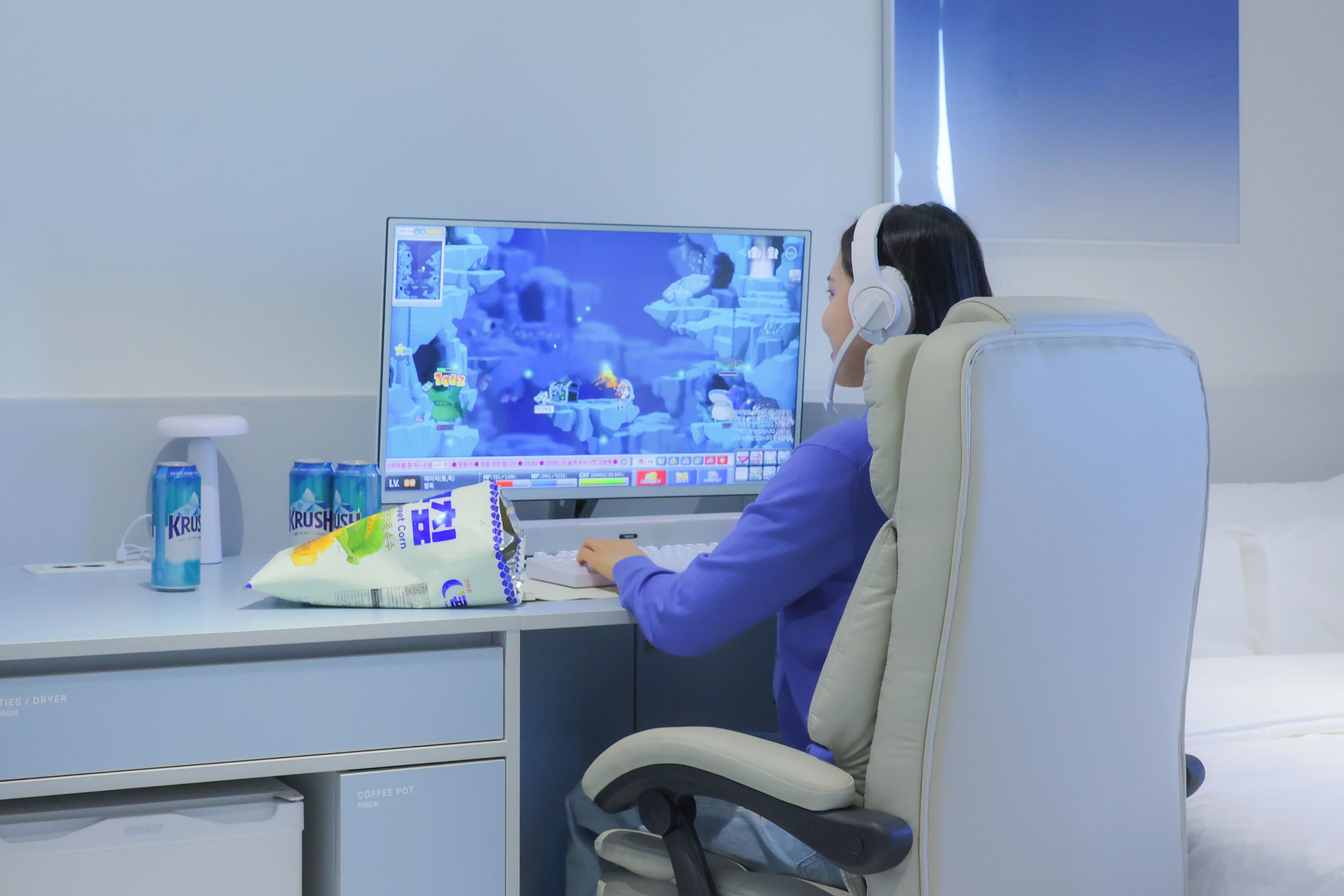 A person sitting at a desk with a computer, a coffee pot, and a bag of tissues.