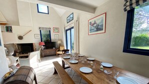 A dining area with a wooden table set for four, a fireplace, and a television in the background.