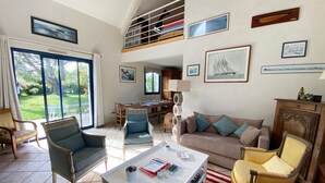 A spacious living area with a high ceiling, a dining table, and a sofa.