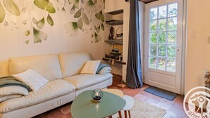 Un salon confortable avec un canapé, une petite table et une fenêtre avec des rideaux.