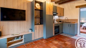 Une cuisine compacte avec des meubles en bois, un four encastré et un téléviseur fixé au mur.