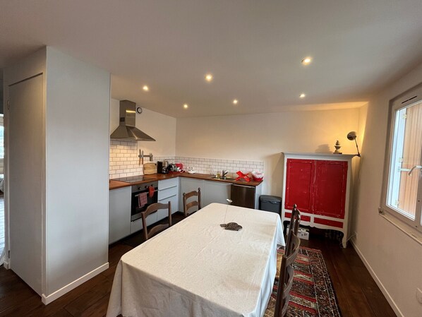 A compact kitchen with a dining area, featuring a stove, sink, and cabinets.