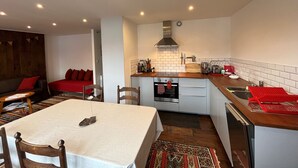 A compact kitchen with a dining area, featuring a central island, built-in oven, and white tiled backsplash. - Charming 2-room apartment in Villard de Lans center (Villard-de-Lans)