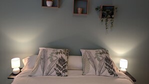 Une chambre à coucher avec un lit, deux lampes de chevet et trois étagères murales sur lesquelles sont disposés divers objets.