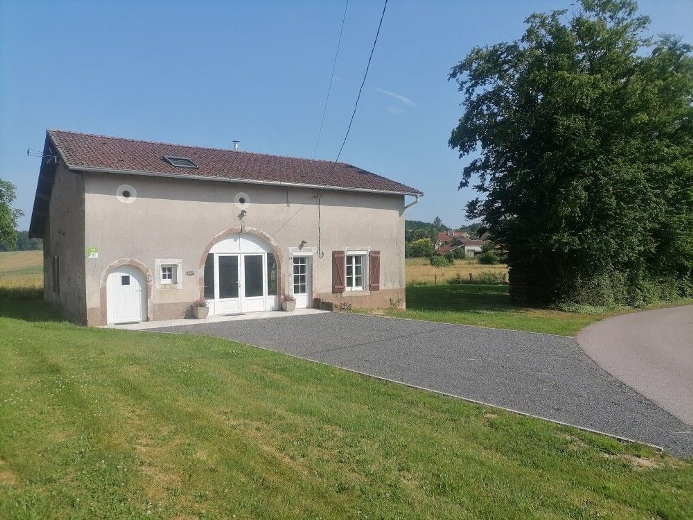 A single-story building with a tiled roof, a central entrance with a door and windows, and a paved driveway.