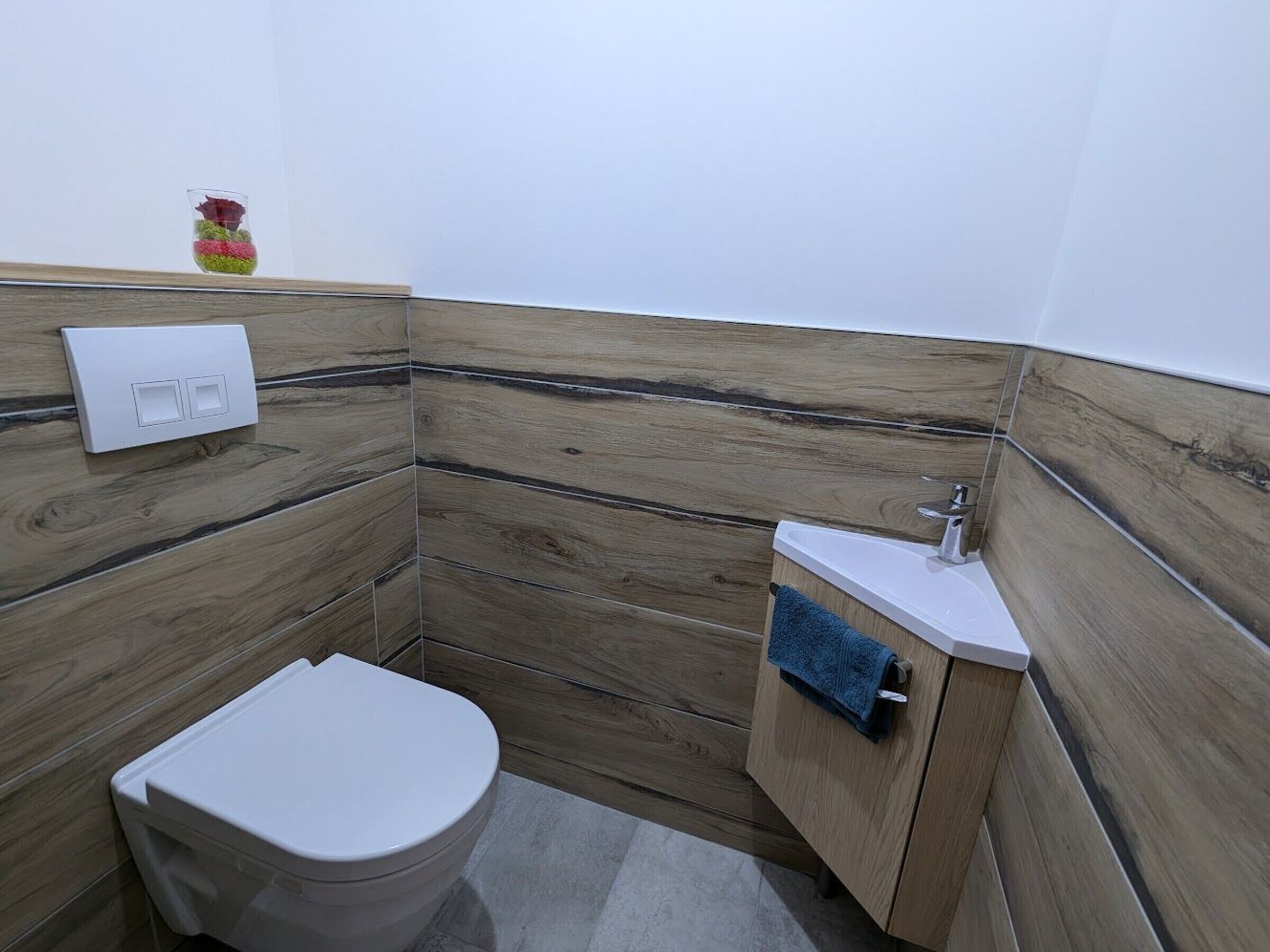 Un baño pequeño con inodoro, lavamanos y una toalla colgada en la pared.