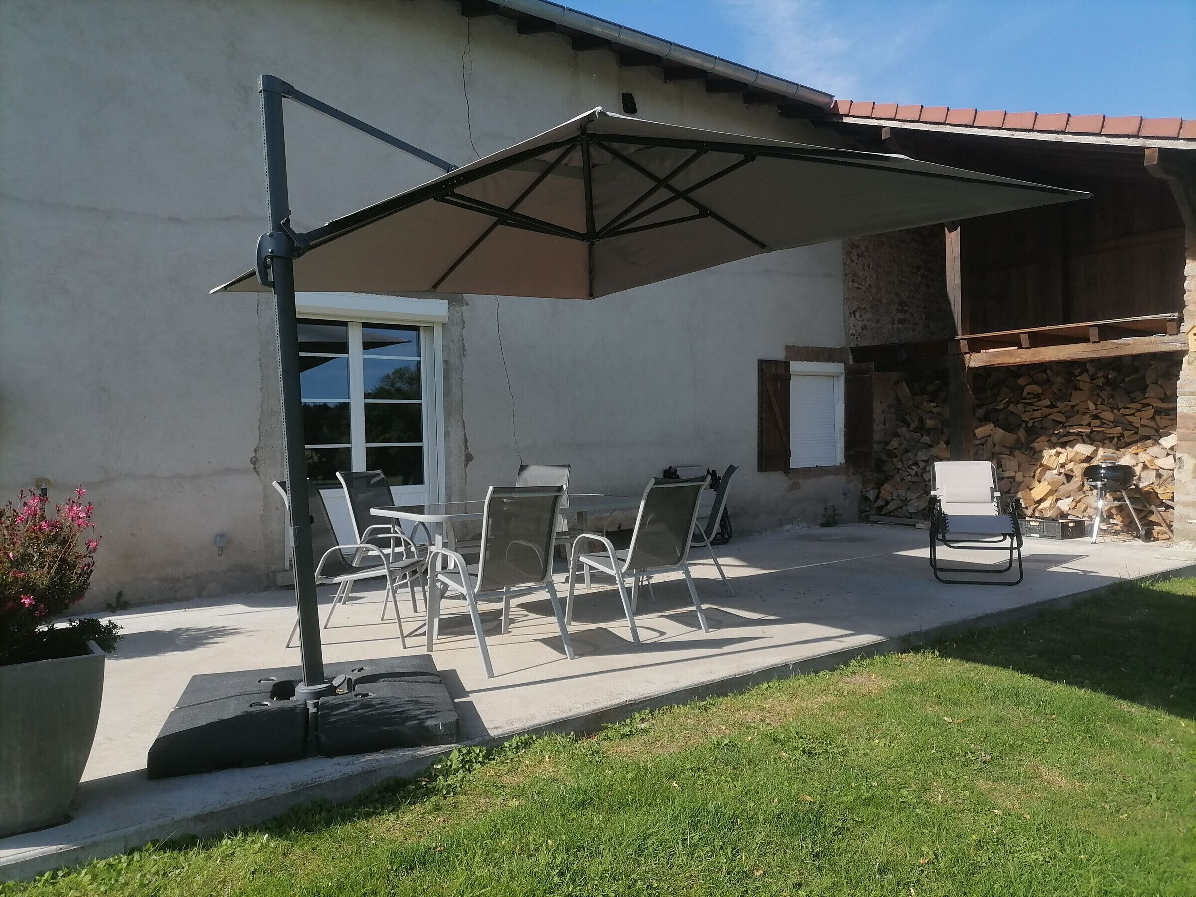 A patio with outdoor furniture, a pergola, and a stone wall.