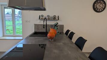 A modern kitchen with a built-in oven, a sink, and a dining area with chairs.