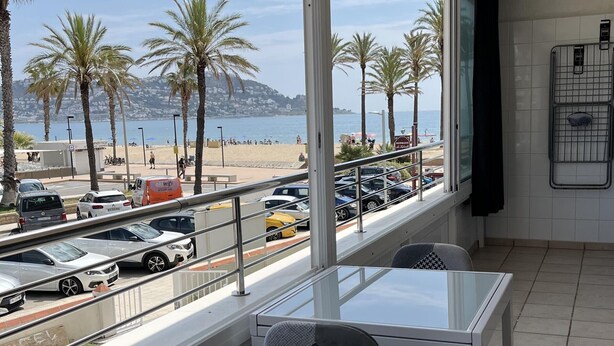 A hotel room with a balcony overlooking a beach, cars parked outside, and a view of the sea. - Beautiful 3-room apartment in Roses with pool and garden, beach access (Roses)