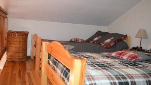 A small, cozy room with a single bed, a wooden headboard, a wicker basket, and a nightstand with a lamp.