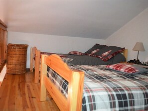 Una habitación pequeña y acogedora con una cama individual, cabecera de madera, una cesta de mimbre y una mesita de noche con lámpara.