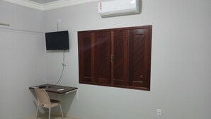 A room with a desk, chair, TV, wardrobe, and air conditioning unit. - Hotel Toronto  (Paragominas)