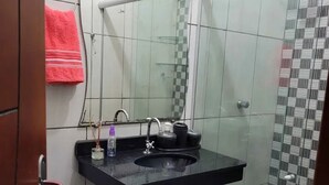 A bathroom with a black countertop sink, a mirror, and a glass shower enclosure. - Hotel Toronto  (Paragominas)